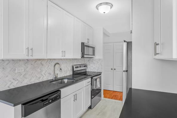 Unit 31D - completed kitchen with painted shaker cabinets, herringbone backsplash, and quartz counter