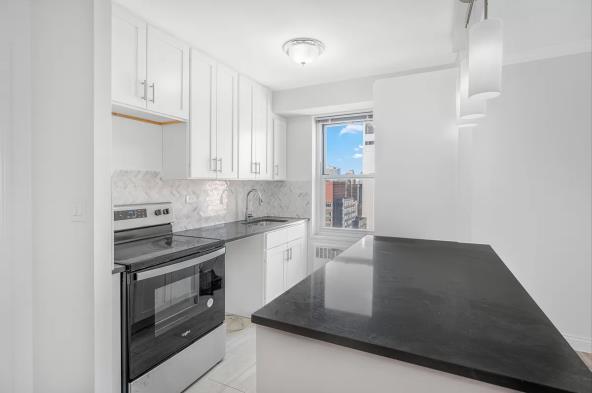 Unit 29J - completed kitchen with white cabinetry, quartz peninsula, and skyline view